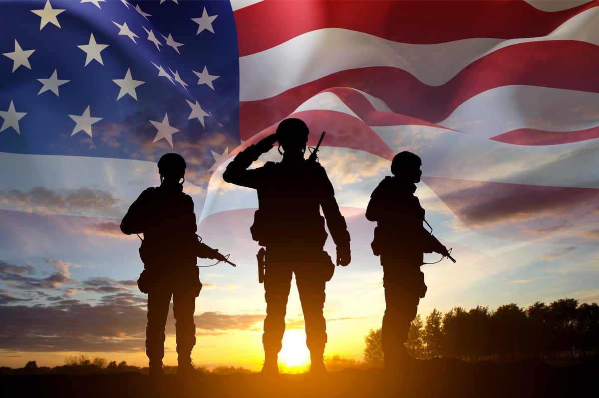 Silhouettes of a soldiers with USA flag against the sunset. Veterans Day, Memorial Day concept