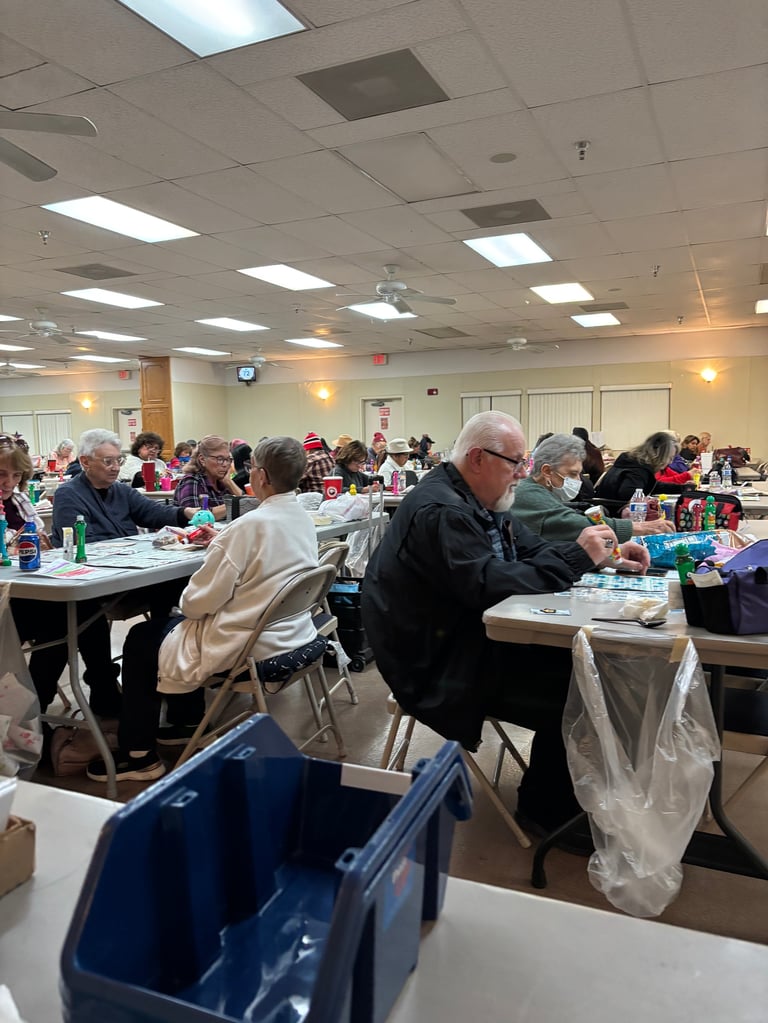 Group of seniors seated at tables in a community center or cafeteria during a meal or gathering event
