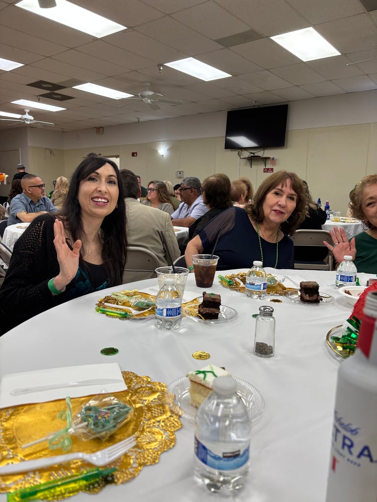 Group of people dining at a table with food and beverages during an indoor event or banquet