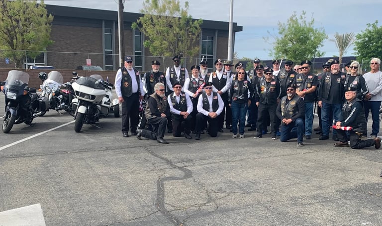 Large group of people in black vests and motorcycles gathered in a parking lot outside a brick building