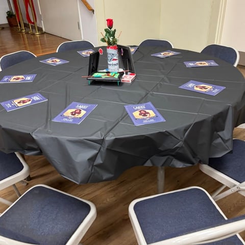 Round table with gray tablecloth covered with playing cards, centered with a red rose and decorative items