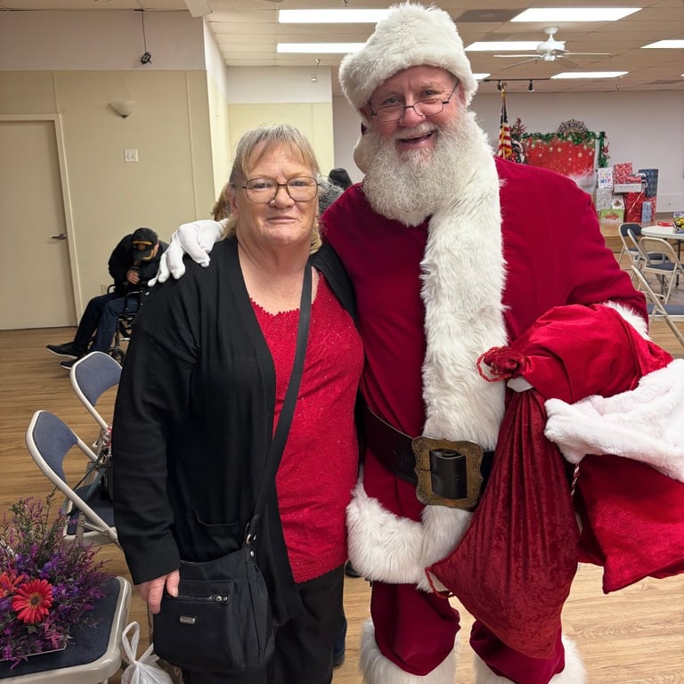 Woman in black jacket posing with Santa Claus in red suit with white fur trim and beard indoors