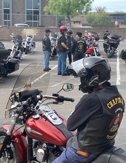 Group of motorcycle riders in leather vests gathered in a parking lot with their bikes during a motorcycle club meetup