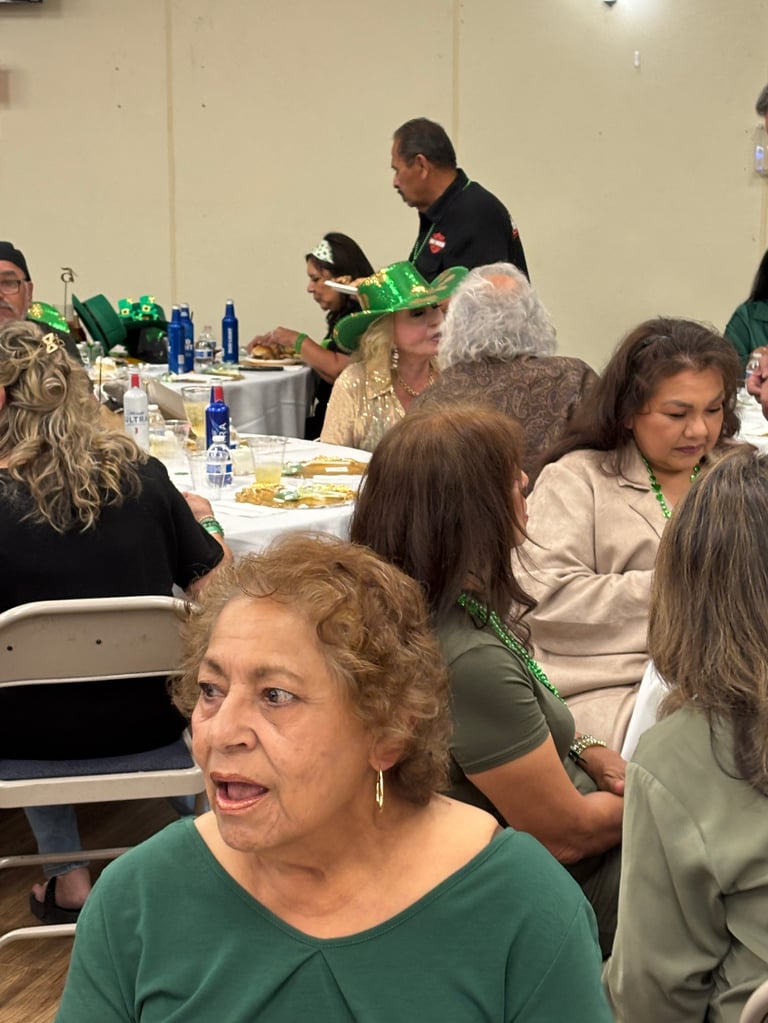 Group of people dining together at a table during a St. Patricks Day celebration with green decorations and festive attire